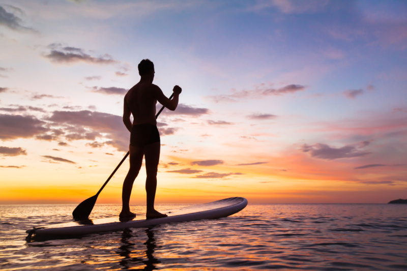 coucher de soleil avec une personne de dos sur un paddle